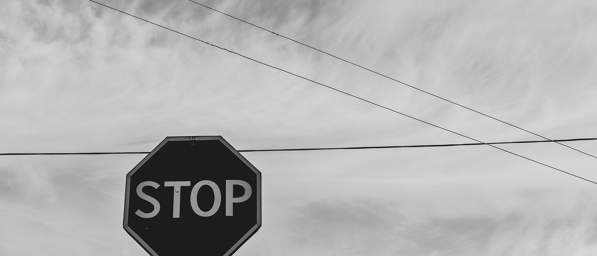 grayscale-photography-of-stop-signage-under-sky-1585711