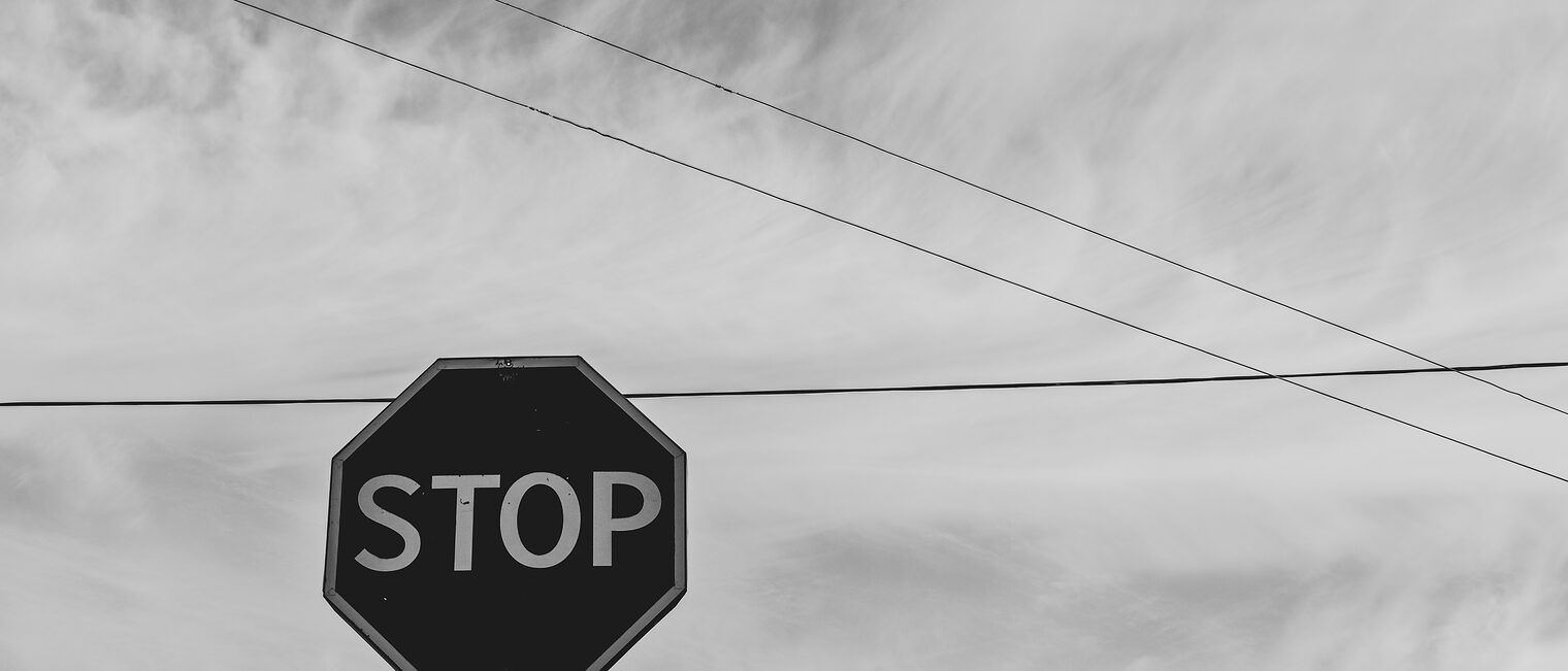 grayscale-photography-of-stop-signage-under-sky-1585711