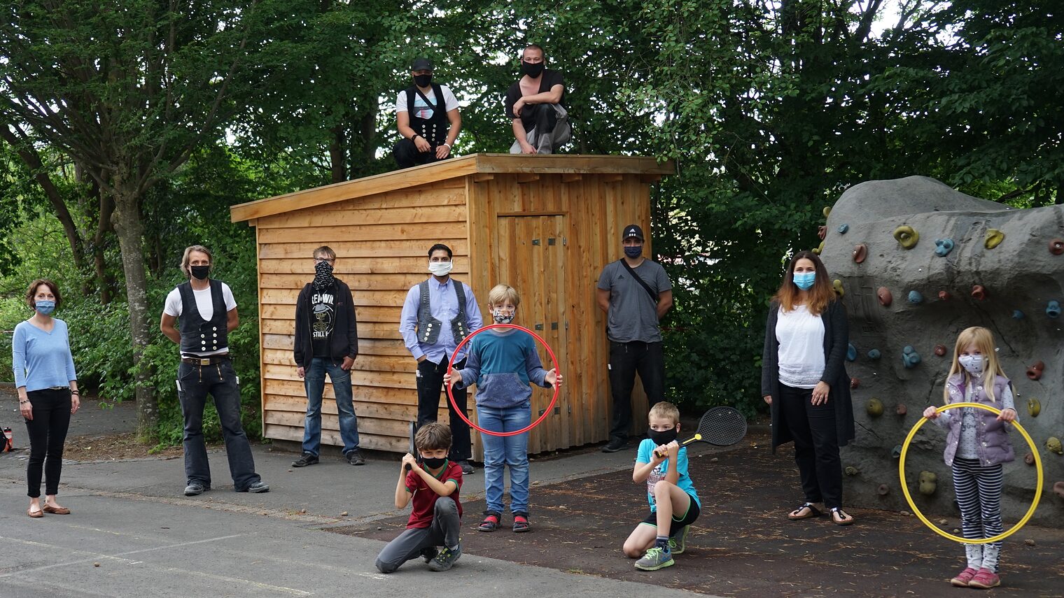 In der Pause darf noch nicht gespielt werden: Die Schüler der Grundschule Herberhausen proben aber schon einmal für das Foto den echten Einsatz der Spielgeräte. BBZ-Lehrwerkmeister Ulrich Hoinkhaus (2. v. li.) hat mit seinen Fachpraktikern im Zimmererhandwerk das Holzhäuschen für Kleinspielgeräte an Schulleiterin Karin Limbach (li.). und Stefanie Bleyer (2. v. re.), Vorstand des Fördervereins, für die Zeit nach Corona offiziell übergeben.