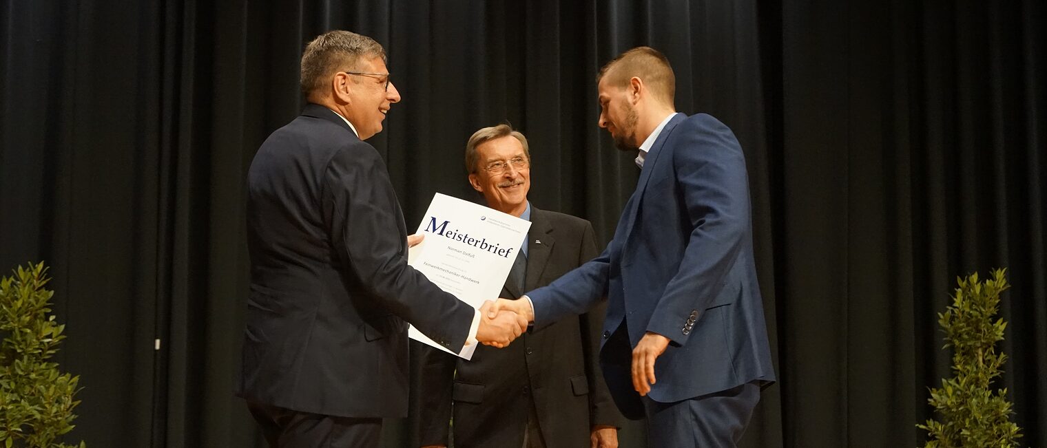 Erwin Kostyra (Mitte), Präsident der Bundesverbands Metall, und Delfino Roman (li.), Präsident der Handwerkskammer Hildesheim-Südniedersachsen, überreichen den Absolventen des BFM die Meisterbriefe in den metallverarbeitenden Handwerken. 