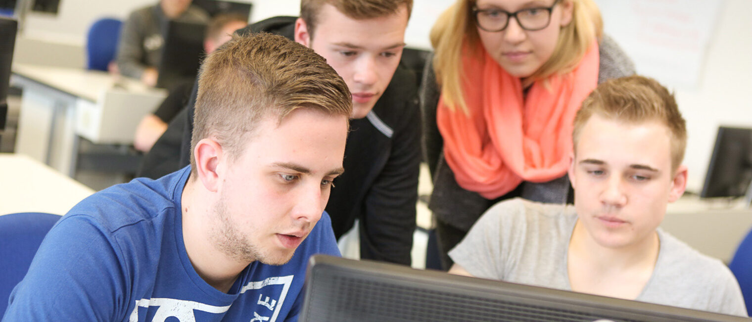 Seminar Teilnehmer schauen gemeinsam auf einen Monitor Auszubildende nehmen an einem Seminar teil und schauen in einer Gruppe auf einen Computerbildschirm